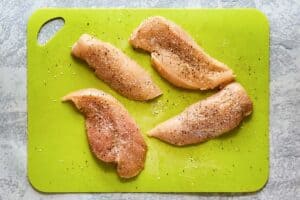 four raw seasoned chicken breast pieces.