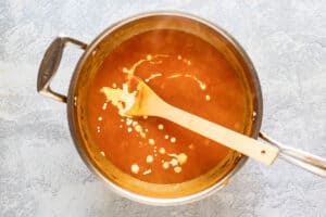 adding cream to pumpkin curry soup in a pot.