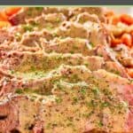 closeup of yankee pot roast slices with gravy and vegetables on a platter.