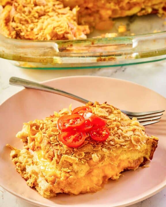 overnight breakfast strata serving on a plate in front of the strata.