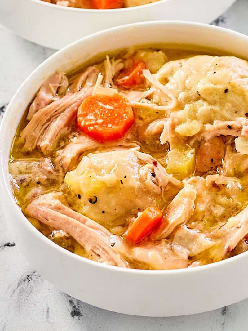 closeup of homemade chicken and dumplings in a white bowl.