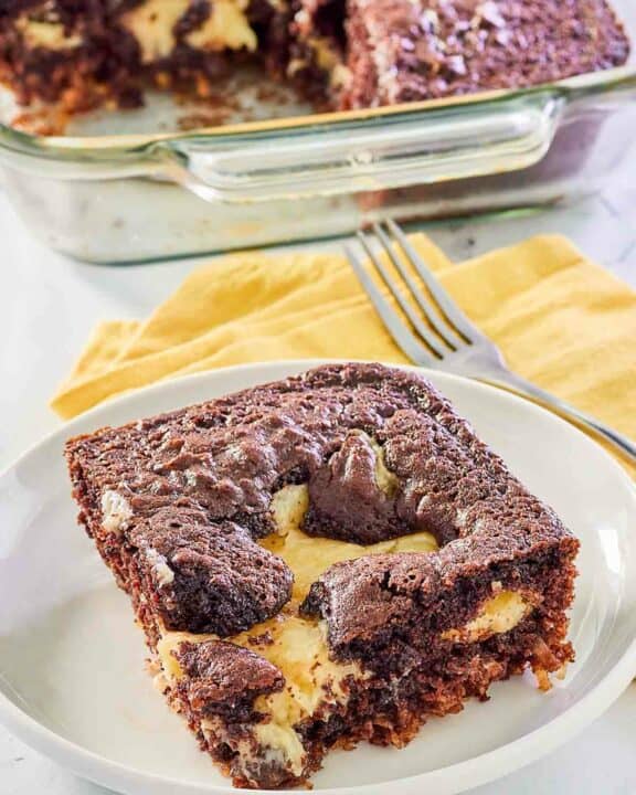 slice of earthquake cake on a plate in front of the cake in a baking dish.
