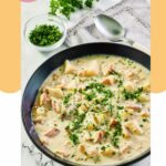 a bowl of clam chowder, a spoon, and parsley.