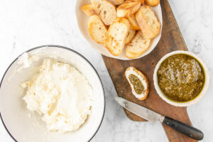 adding pesto on top of goat cheese crostini.