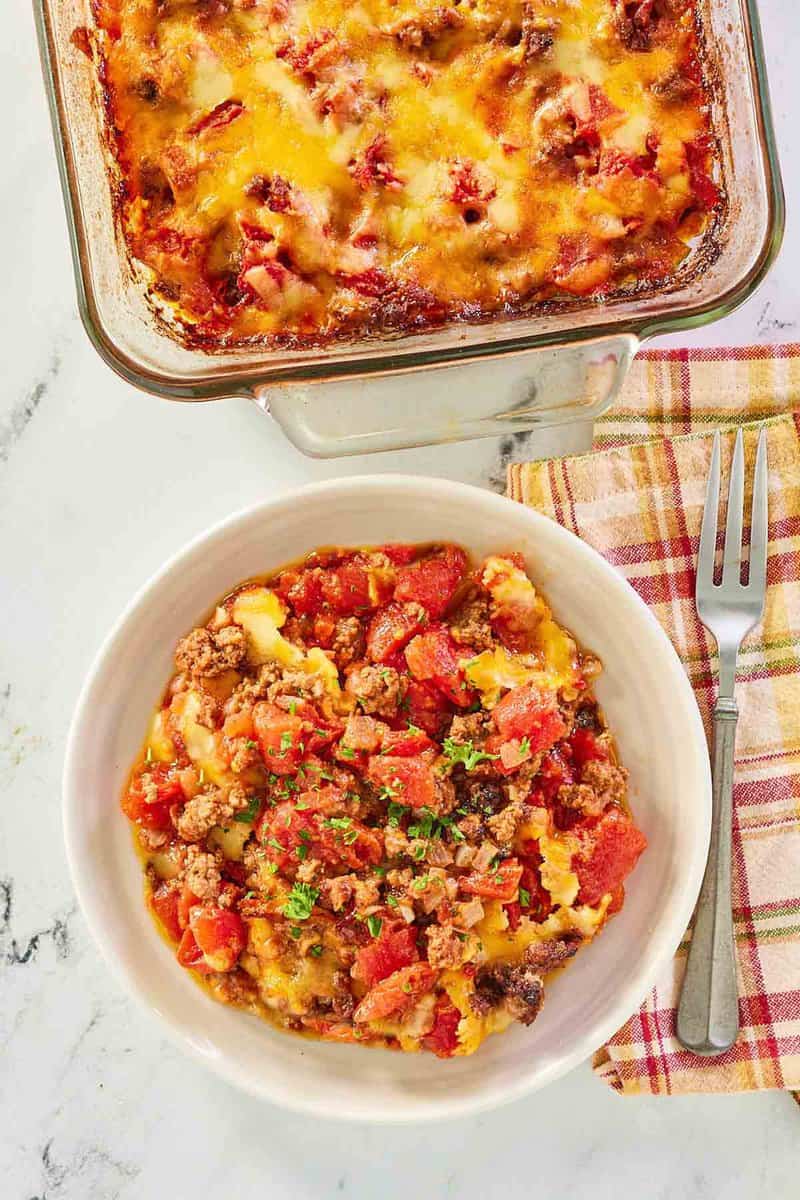 overhead view of hamburger hash with cheese in a baking dish and bowl.