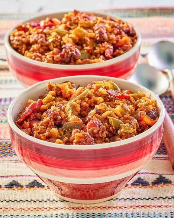 two bowls of Mexican rice casserole and spoons next to them.