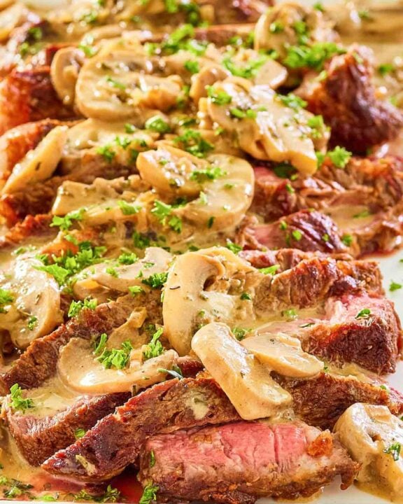steak marsala with sauce on a white platter.