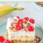 slice of banana split cake with cherries and pecans on top.