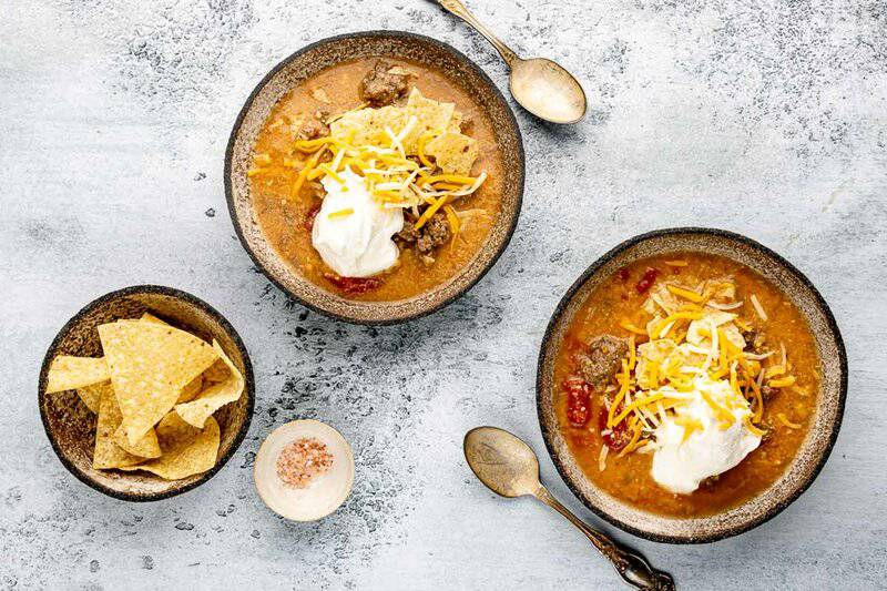 overhead view of copycat Luby's beef tortilla soup and tortillas in bowls.