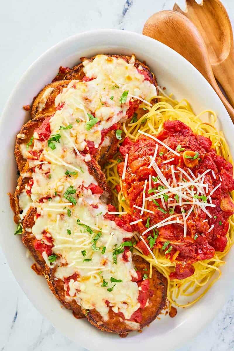 overhead view of copycat Olive Garden eggplant parmigiana, pasta, and marinara on a platter.