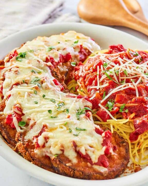 copycat Olive Garden eggplant parmigiana, pasta, and marinara on a platter.