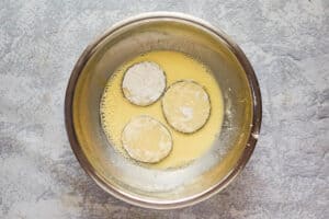 seasoned floured eggplant slices in egg wash.