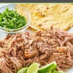 pulled roasted pork shoulder, lime wedges, tortillas, and cilantro.