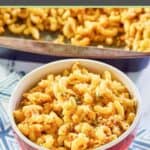 a serving of spicy macaroni and cheese in a red striped bowl.