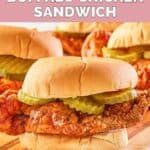 homemade wingstop buffalo chicken sandwich with pickles on a wood board.