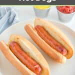 Two air fried hot dogs in buns on a white plate.