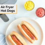 Overhead view of two air fried hot dogs and buns on a plate.