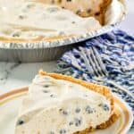 blueberry cream pie slice on a plate and the pie behind it.