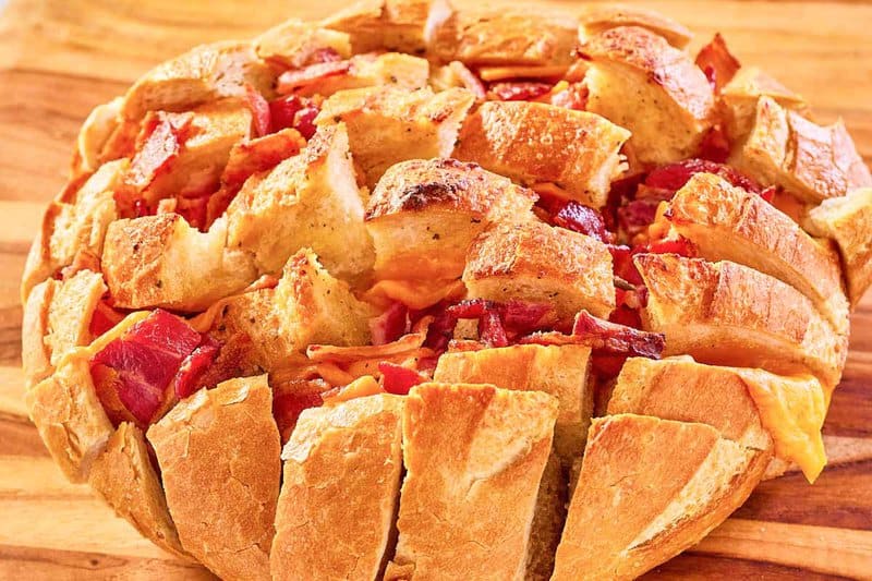 cheddar bacon ranch cheesy pull apart bread on a wood serving board.
