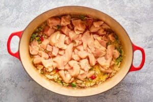 raw chicken pieces over a rice mixture in a Dutch oven.