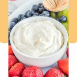 A bowl of cream cheese fruit dip, blueberries, and strawberries.