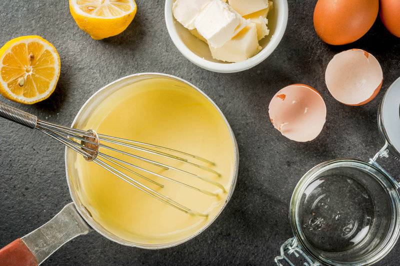 homemade hollandaise sauce in a pan and ingredients around it.