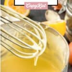 closeup of hollandaise sauce on a whisk over a pan of the sauce.