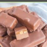 homemade snickers bars piled on a wood board.