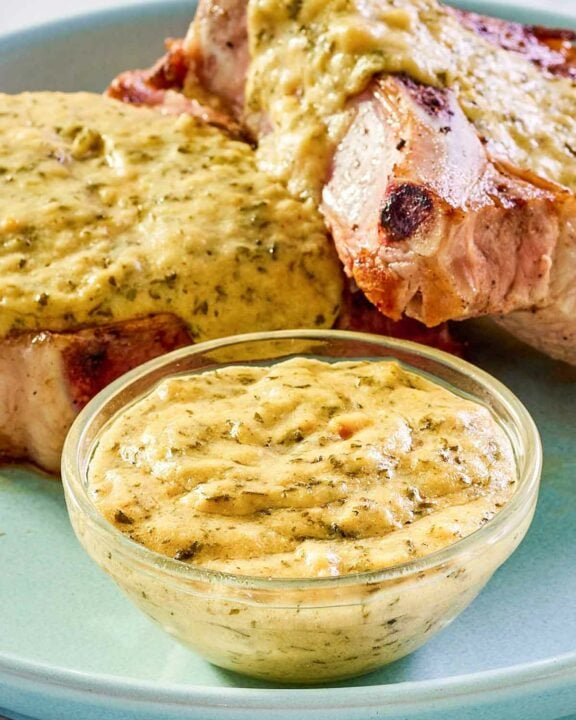 Mustard cream sauce in a small bowl and over pork chops on a plate.