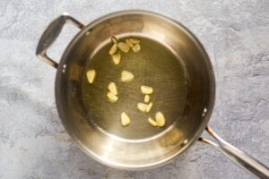 Olive oil and garlic slices in a pan.