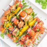 Overhead view of air fryer chicken kabobs on a square white platter.