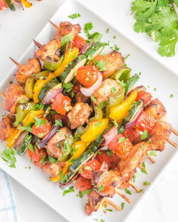 Overhead view of air fryer chicken kabobs on a square white platter.