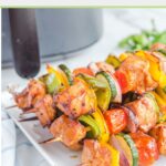 Chicken kabobs in front of an air fryer.