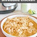 A bowl of homemade Cafe Rio shredded chicken in front on an Instant Pot.