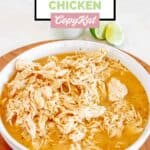 A bowl of homemade Cafe Rio shredded chicken and lime wedges.