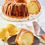 Cream cheese coffee cake on a cake stand and a slice on a plate.