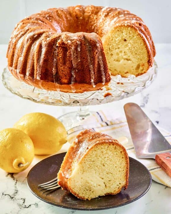Cream cheese coffee cake on a cake stand and a slice on a plate.