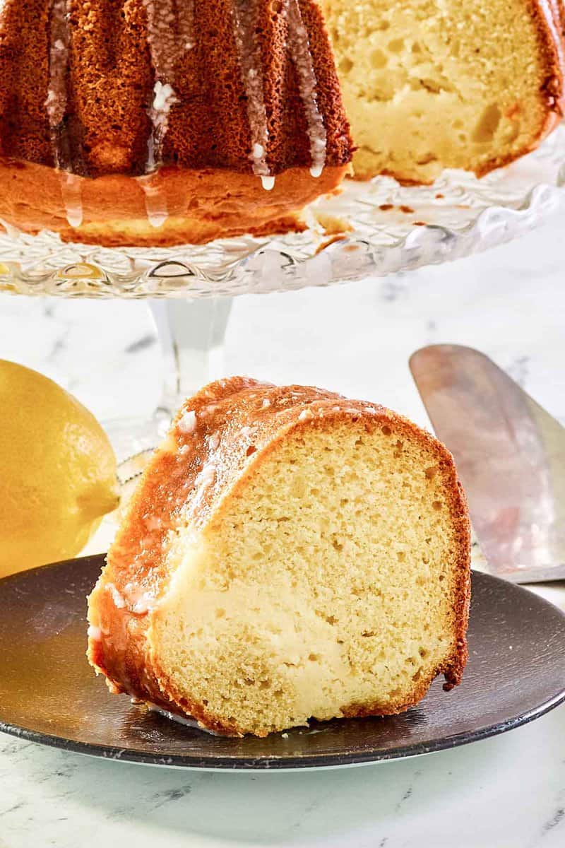 Cream cheese coffee cake slice on a plate in front of the cake.