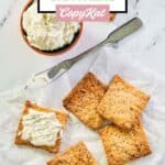 Overhead view of homemade crackers and one with a cheese spread on it.