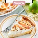 A slice of key lime meringue pie and a fork on a plate.