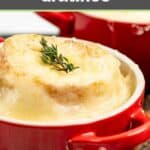 Onion soup gratinee in a red soup crock topped with a thyme sprig.