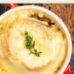 Closeup of onion soup gratinee in a soup crock on a board.