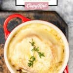 Overhead view of onion soup gratinee in a soup crock on a wood board.