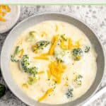 Overhead view of three cheese broccoli soup garnished with shredded cheese.