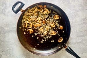 Cooked mushrooms and onions in a skillet.