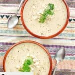 Overhead view of bowls of crab bisque and spoons.