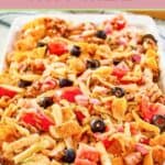 Frito taco salad with catalina dressing on a large white platter.