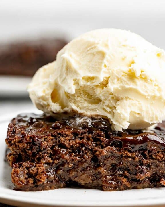 Slice of hot fudge cake topped with ice cream.