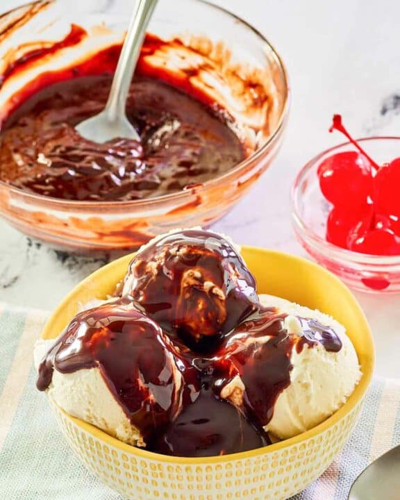 Homemade hot fudge sauce in a glass bowl and on top of ice cream.