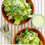 Two Caesar salads and a bowl of copycat Outback Caesar dressing.